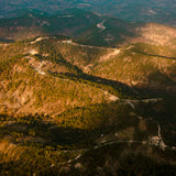 Aerial view of a mountainous landscape with winding roads and greenery.